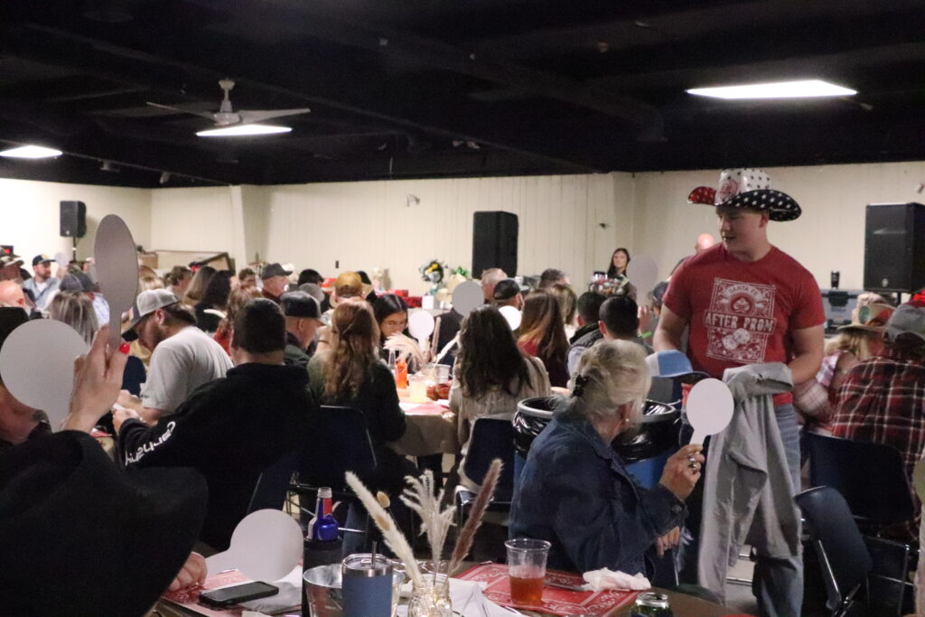 Koewen Dierker delivers auction items to the winning bidder during the Waverly Swim Club Piccadilly, held on March 7. (Santa Fe Times photo by Klarissa Olvera)